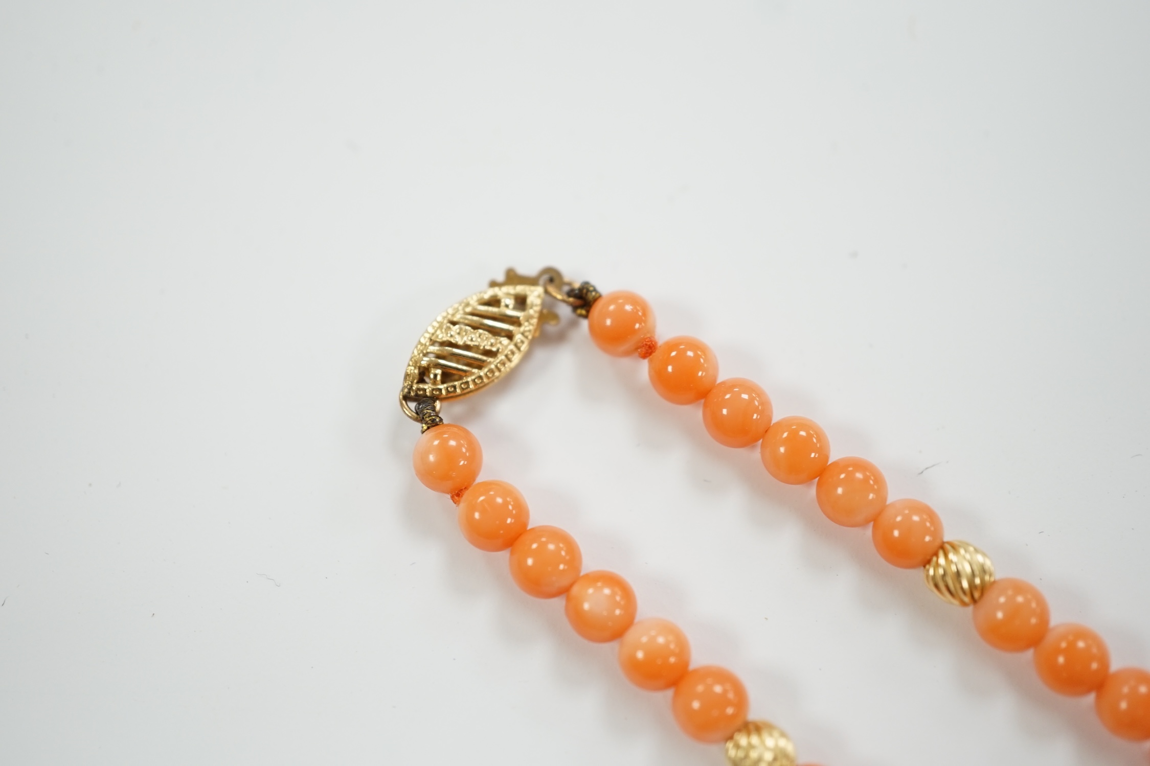 A modern 14k mounted twin strand coral bead necklace, 17cm, together with a 14k mounted single strand coral bead necklace, 44cm.